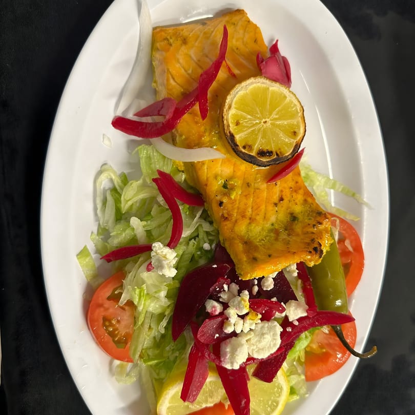 Quruxley Restaurant's grilled salmon with salad, pickled vegetables, feta, and a charred lemon slice.