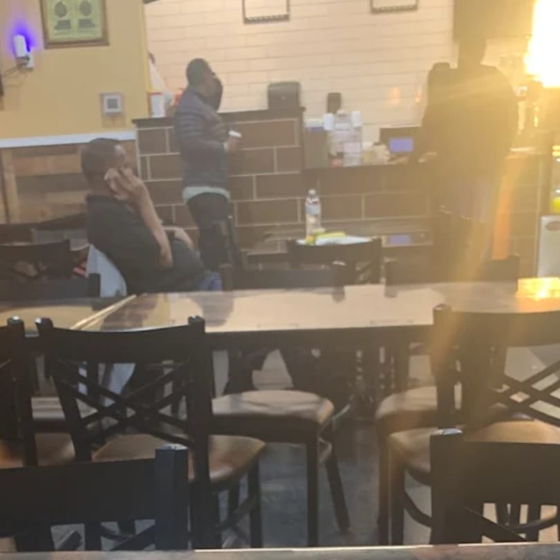 Diners seated at tables and standing near a counter in the dimly lit Quruxley Restaurant.