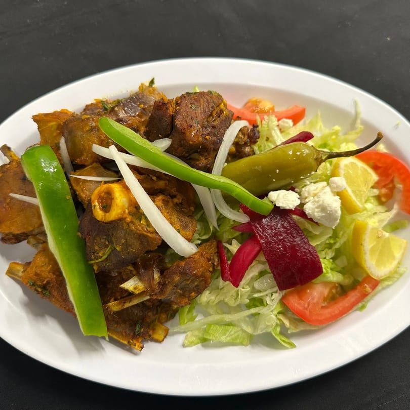 African-style lamb ribs with green peppers, onions, and a side salad with feta, lemon, and tomatoes.