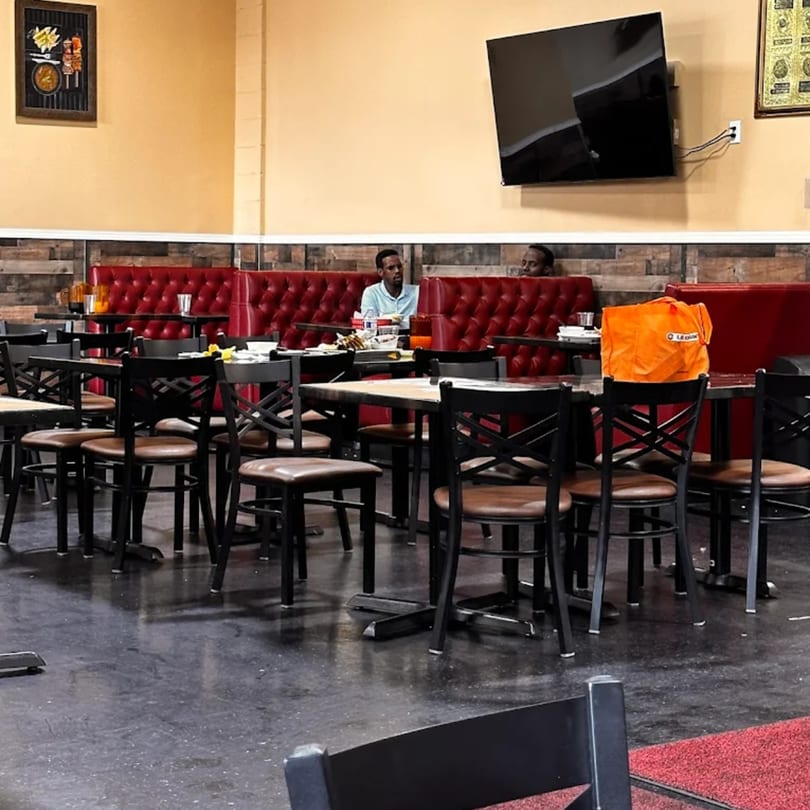 Interior of Quruxley Restaurant with red booths, black tables, and two men seated.